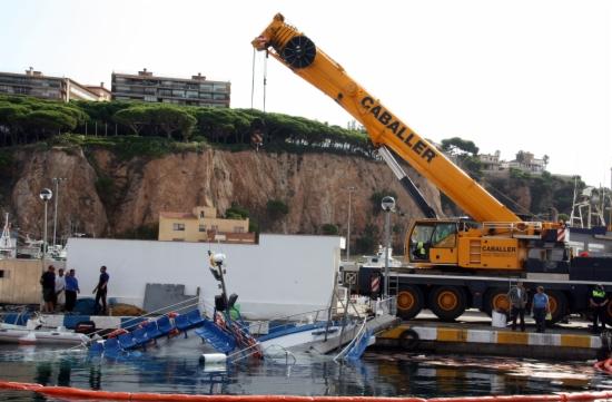 Una grua reflota el vaixell enfonsat al port de Sant Feliu